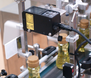 ボトルへの打栓後にキャップの浮きを形状測定センサLSシリーズで全数検査。